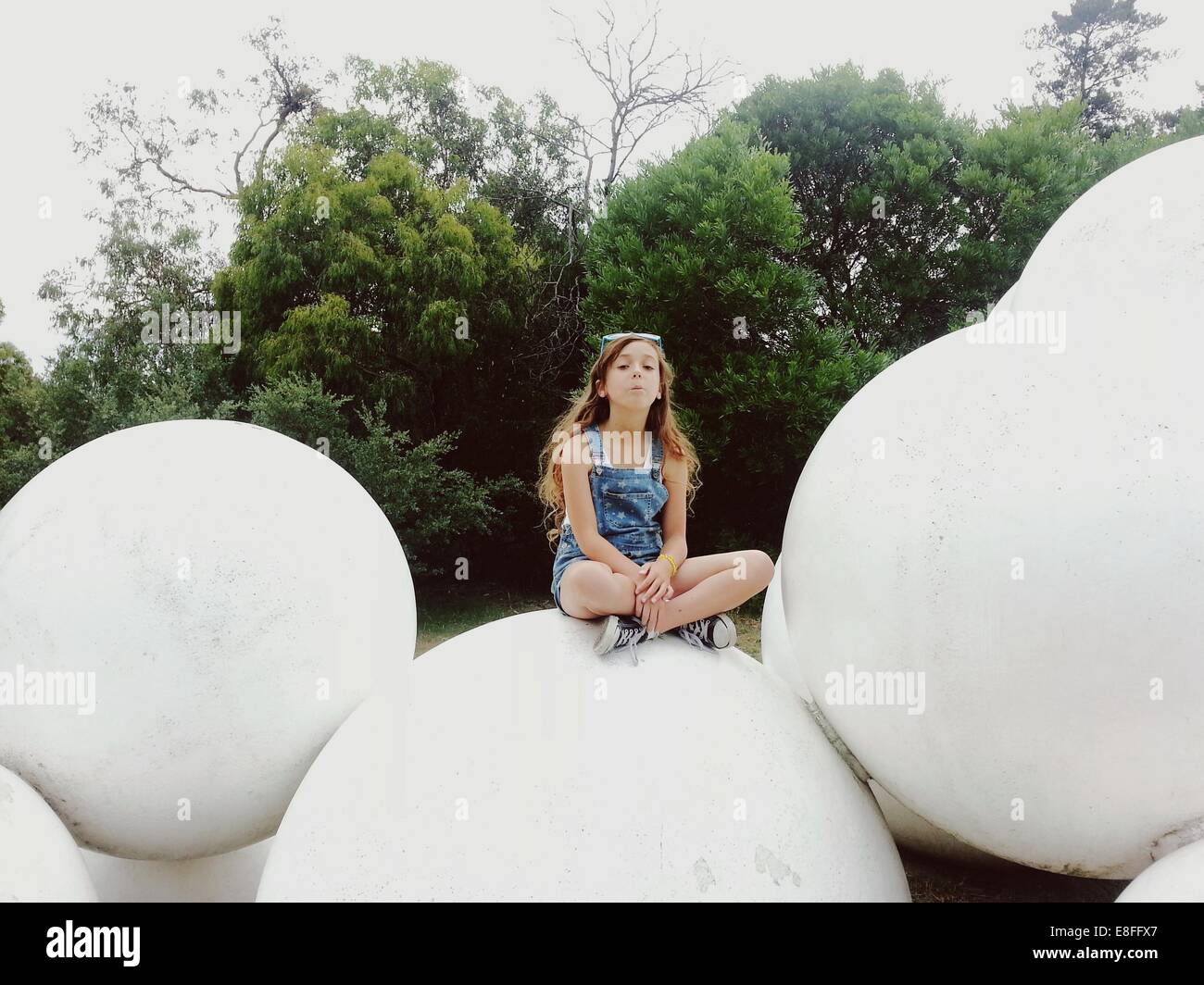 Fille assise sur une sculpture dans un parc, Australie Banque D'Images