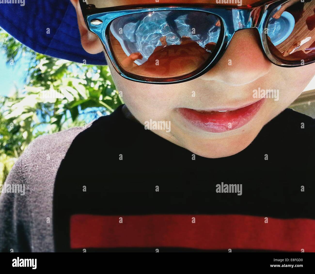 Portrait d'un garçon debout dans une pataugeoire portant des lunettes de soleil Banque D'Images