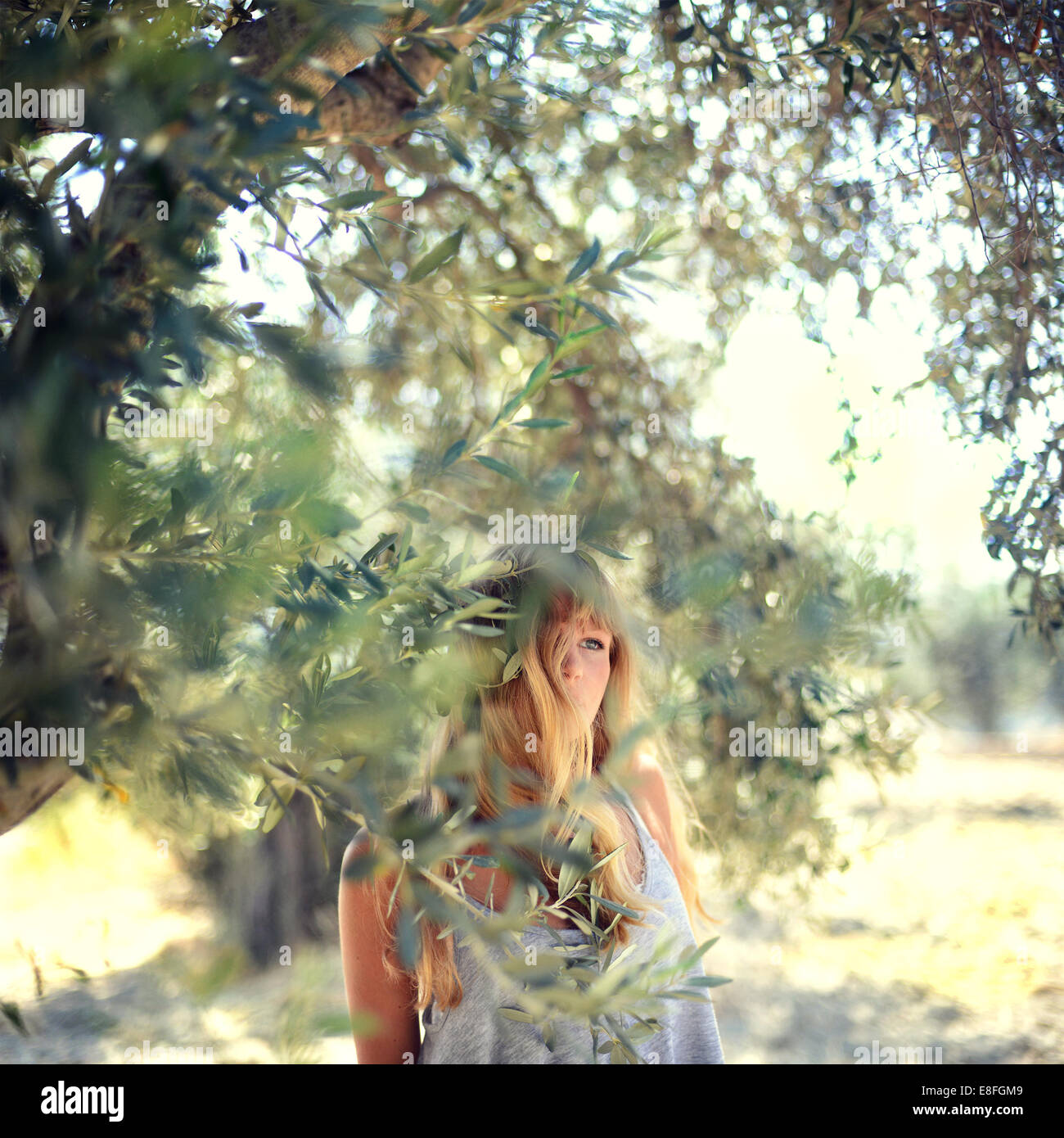 Femme debout dans le jardin par un olivier, Grèce Banque D'Images