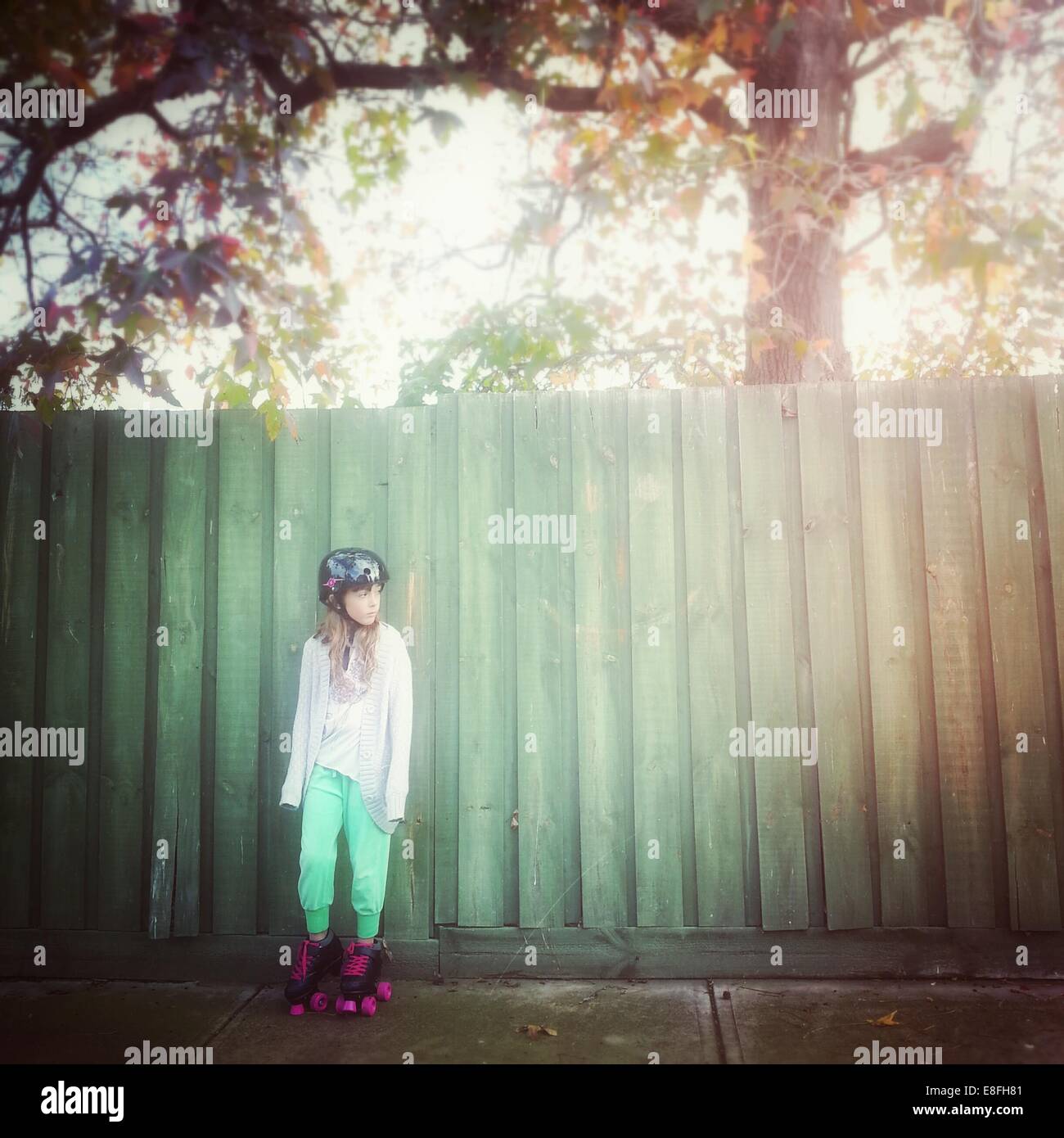 Fille portant des patins à roulettes penche contre la clôture, Australie Banque D'Images