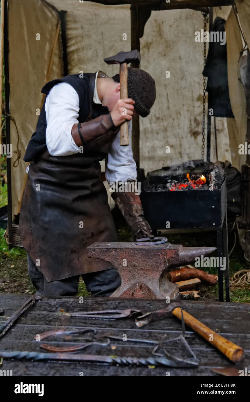 Tablier de cuir en forgeron martelant un fer à cheval sur une enclume Photo  Stock - Alamy