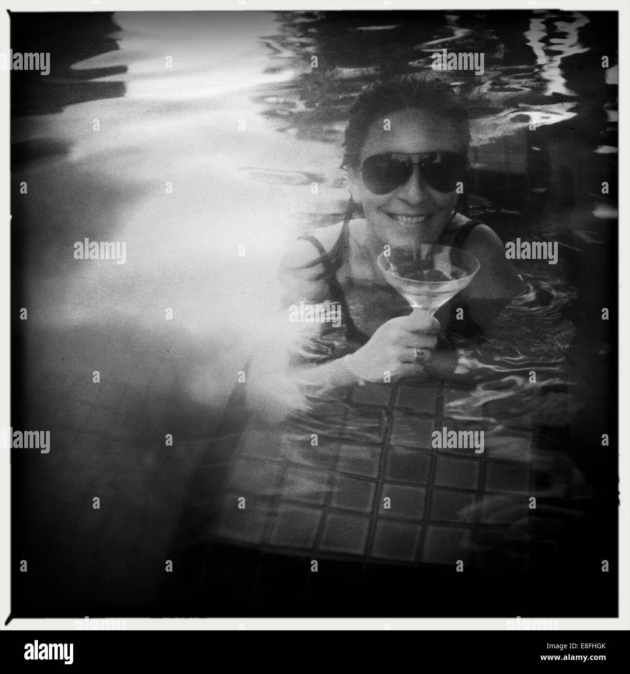 Woman drinking cocktail in swimming pool Banque D'Images