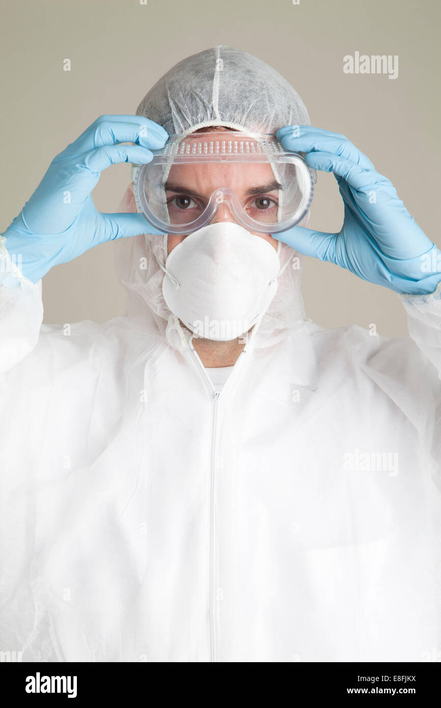 Scientifique portant un costume de protection, un masque et des lunettes de sécurité Banque D'Images