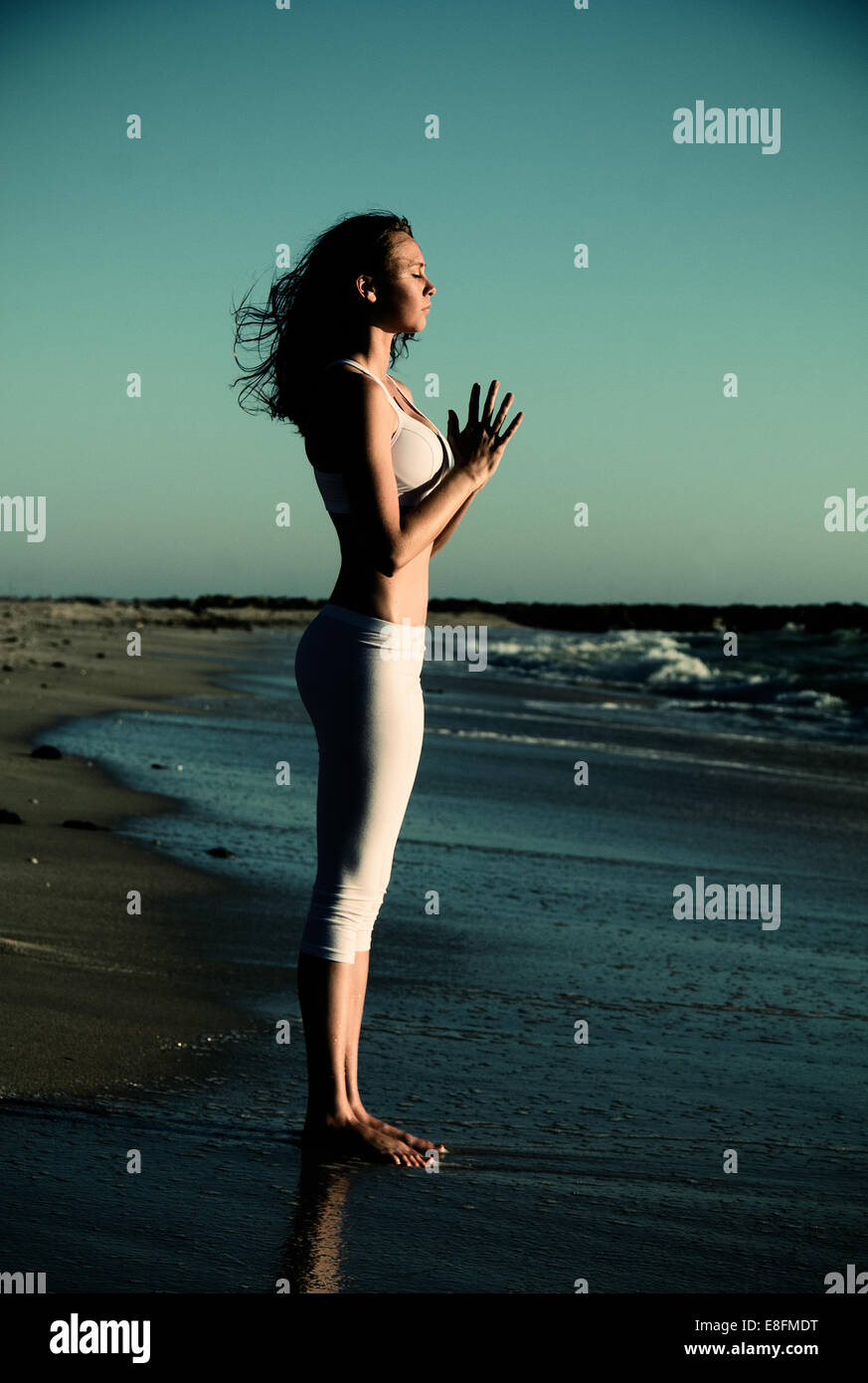 Vue latérale du woman standing on beach faisant du yoga avec les mains en position de prière Banque D'Images