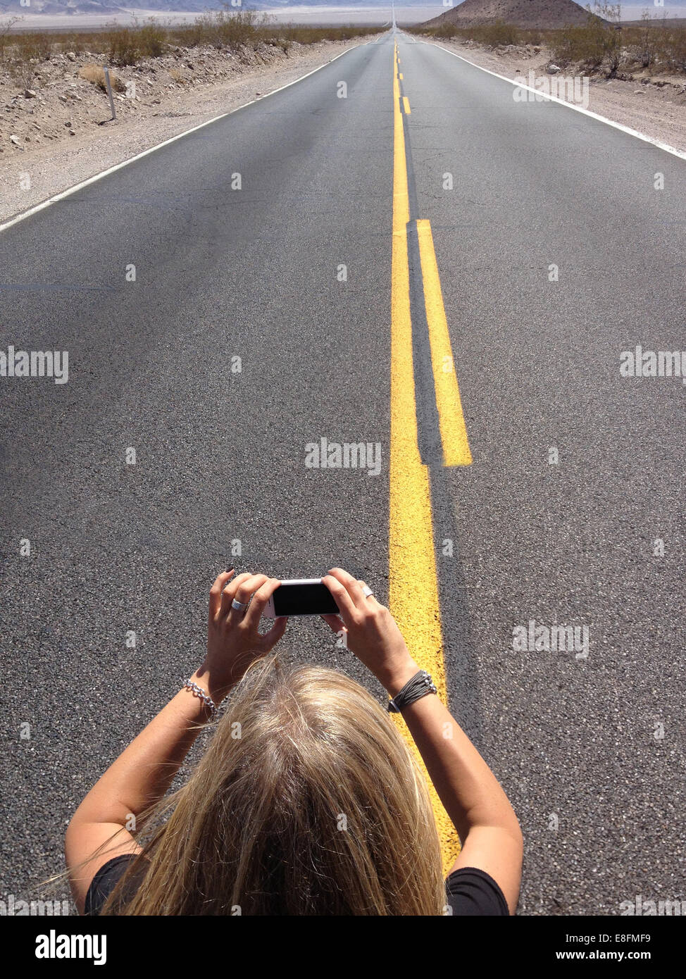 Femme prenant photo de la route à l'infini avec téléphone mobile, Nevada, Etats-Unis Banque D'Images