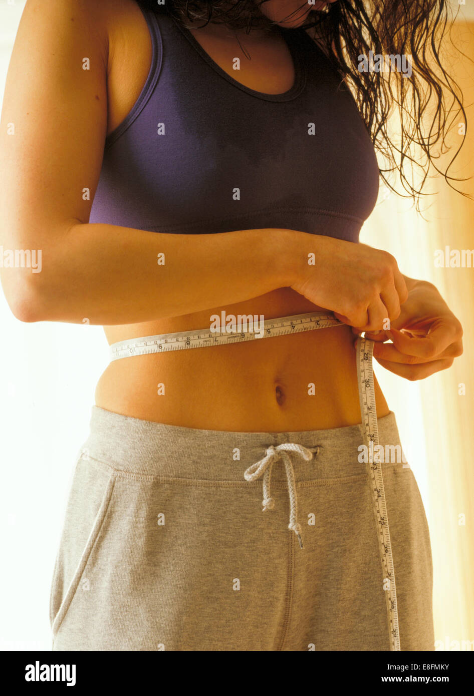 Close-up portrait of a Woman measuring her waist with tape measure Banque D'Images
