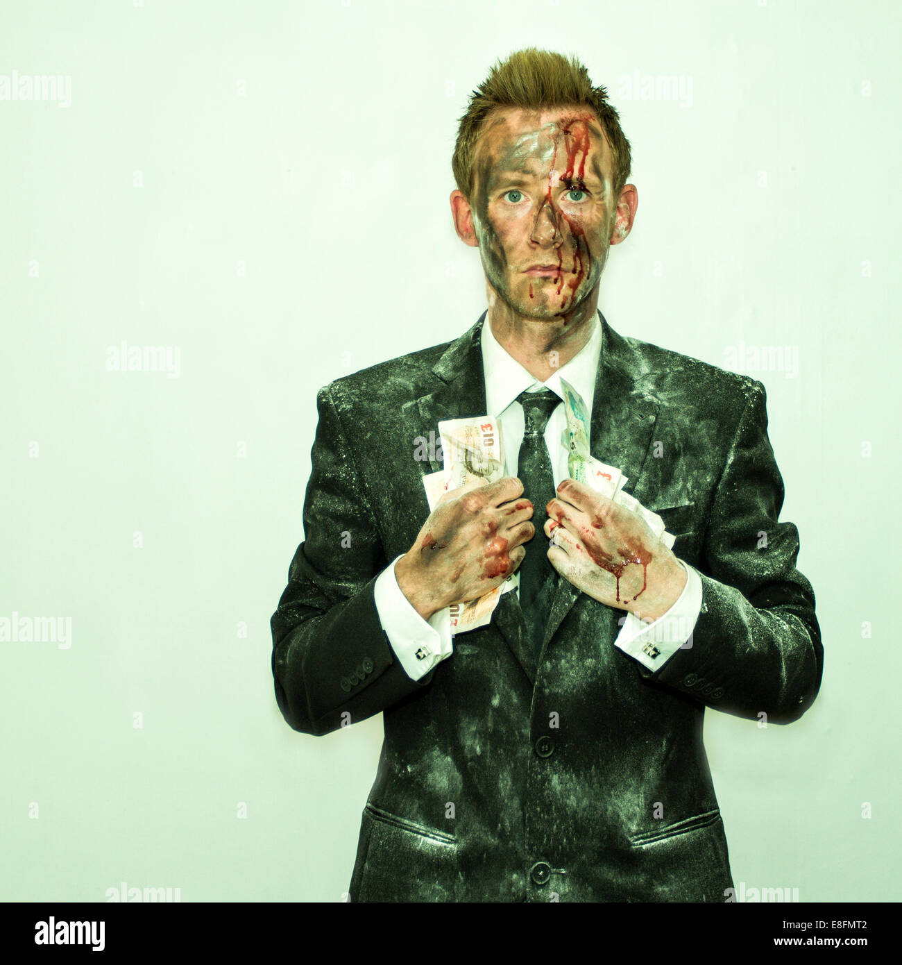 Homme sanglant dans un costume sale tenant une poignée d'argent Banque D'Images