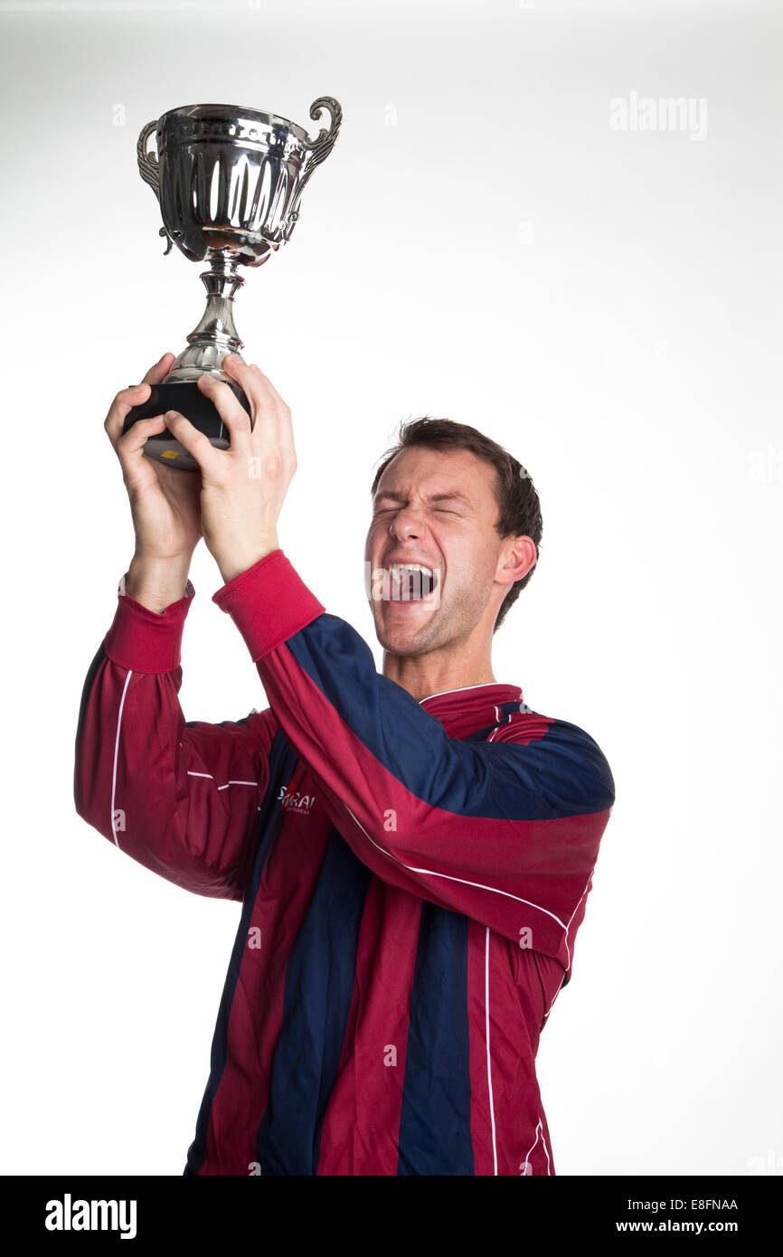 Portrait d'un joueur de football heureux qui soulève un trophée Banque D'Images