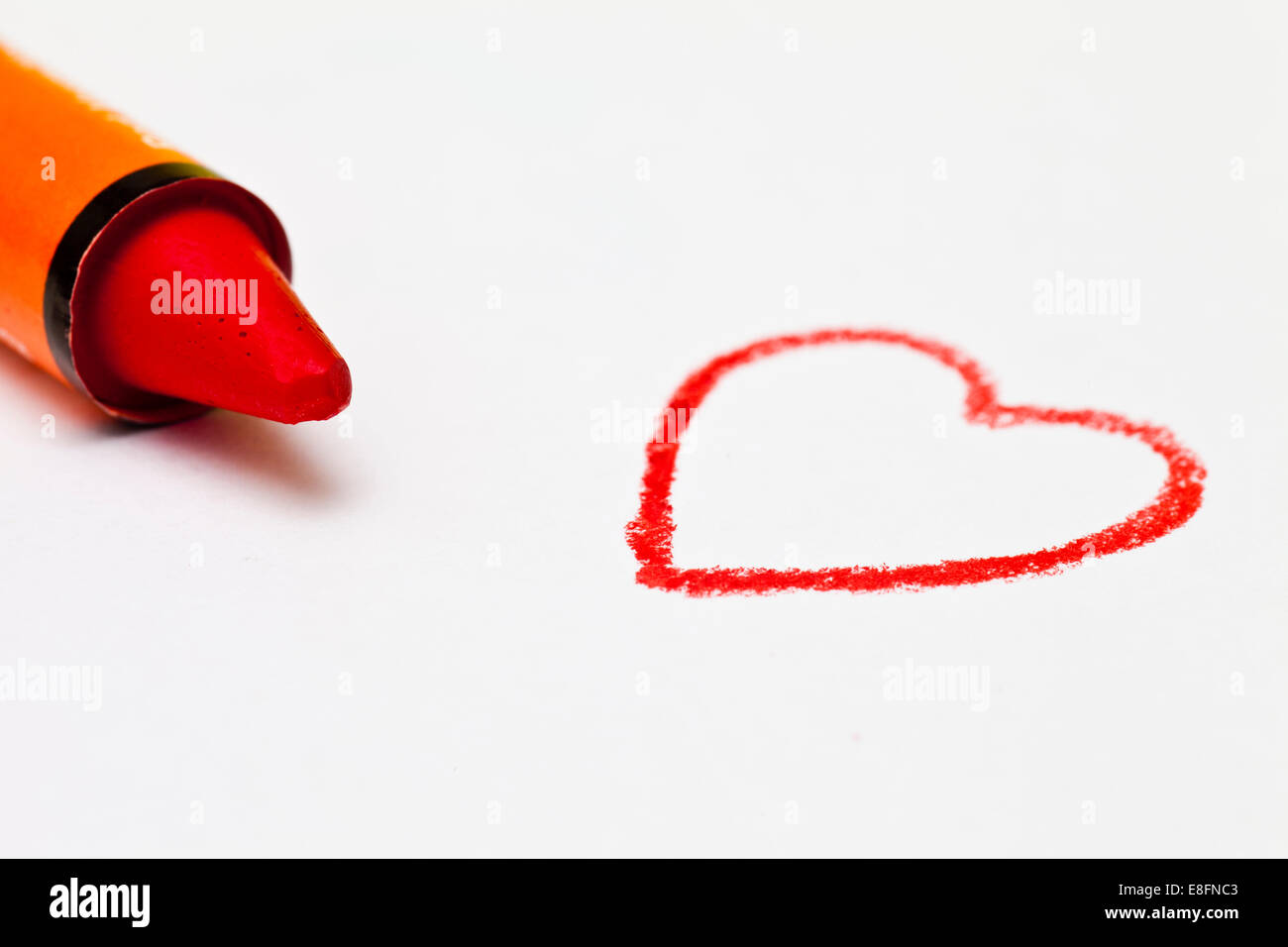 Crayon orange à côté d'un coeur dessin sur un morceau de papier Banque D'Images