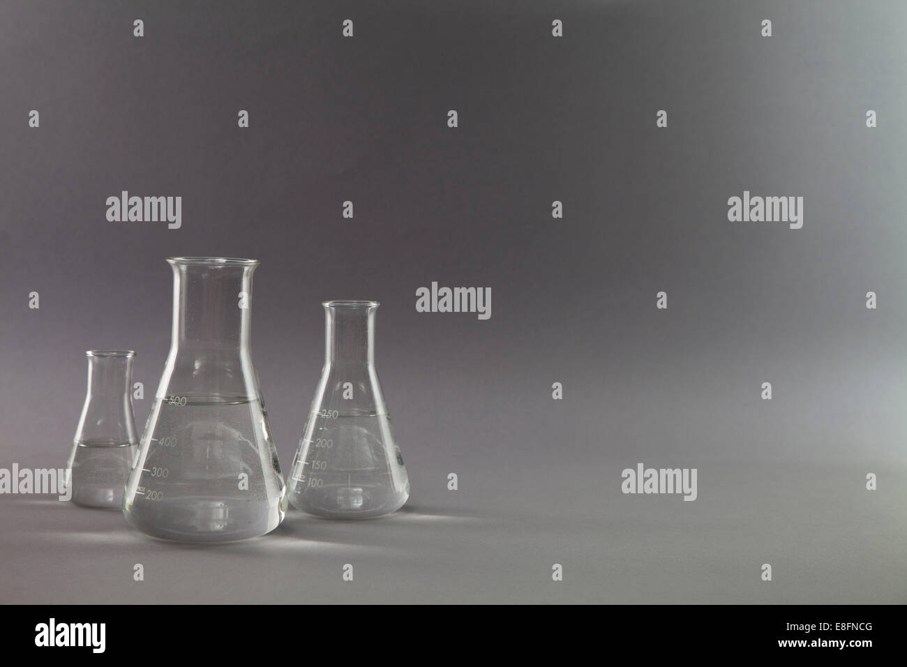 Trois flacons coniques et béchers de mesure remplis de liquide clair dans un laboratoire de recherche Banque D'Images