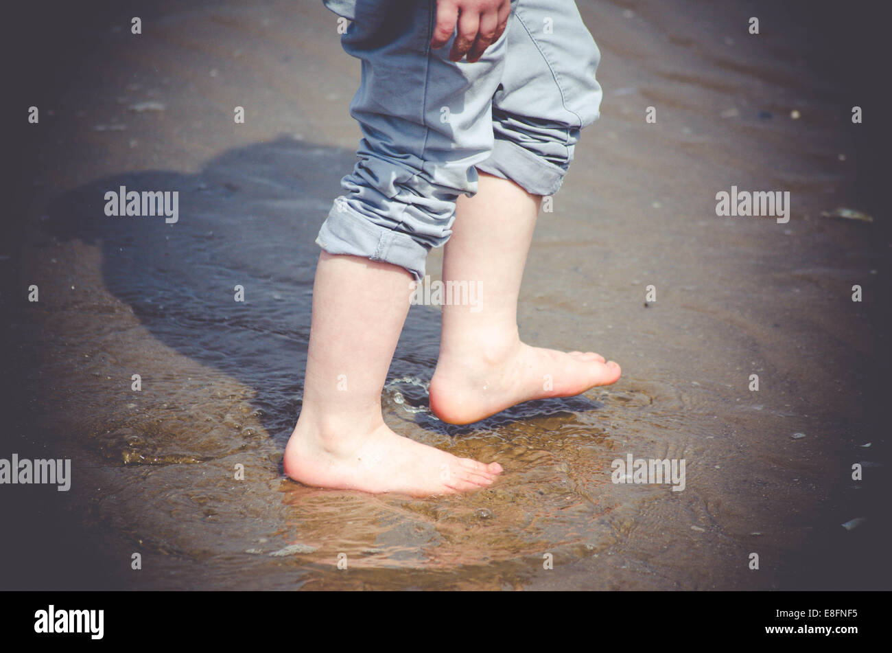Close-up des jambes du garçon walking on beach Banque D'Images