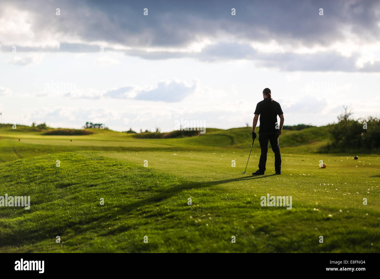 Homme avec golf club donne sur le parcours de golf de tempête Banque D'Images
