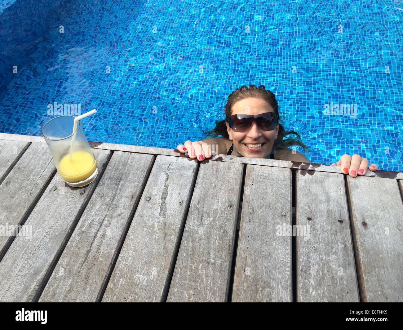 Woman with cocktail relaxing in swimming pool Banque D'Images