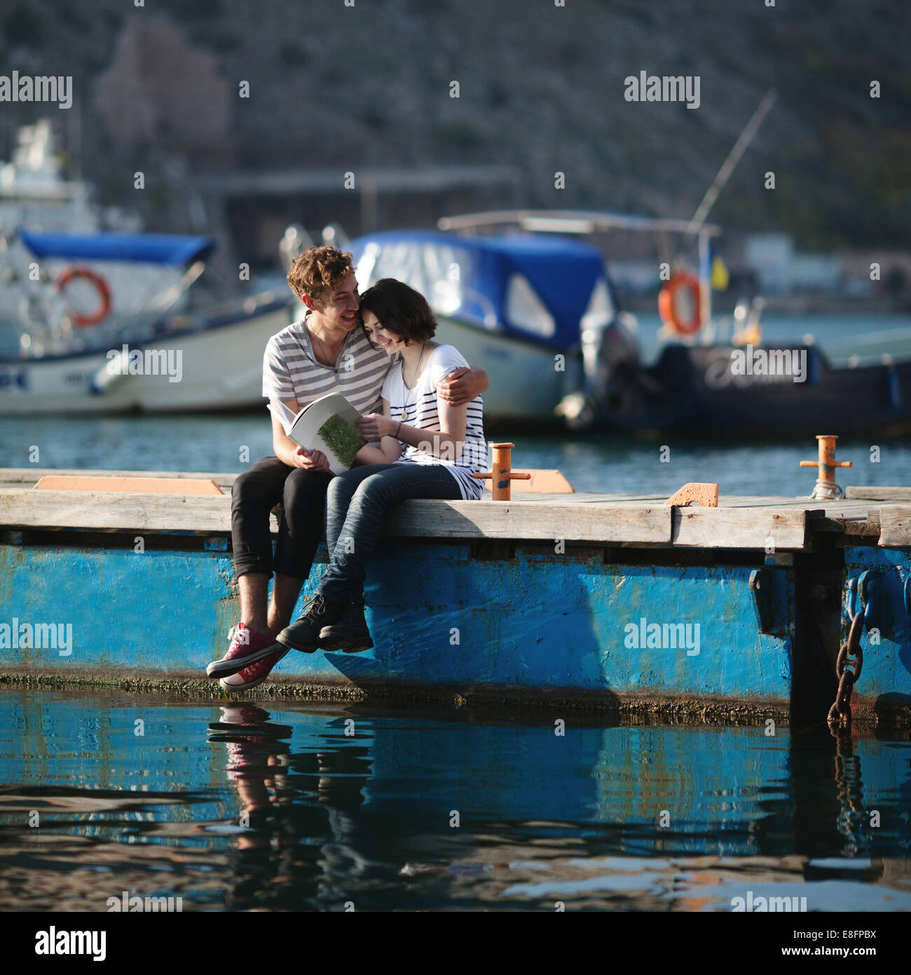 Couple (14-15) sitting on Jetty, embracing Banque D'Images