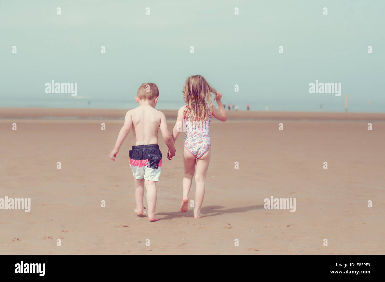 Girl and boy holding hands on beach Banque D'Images