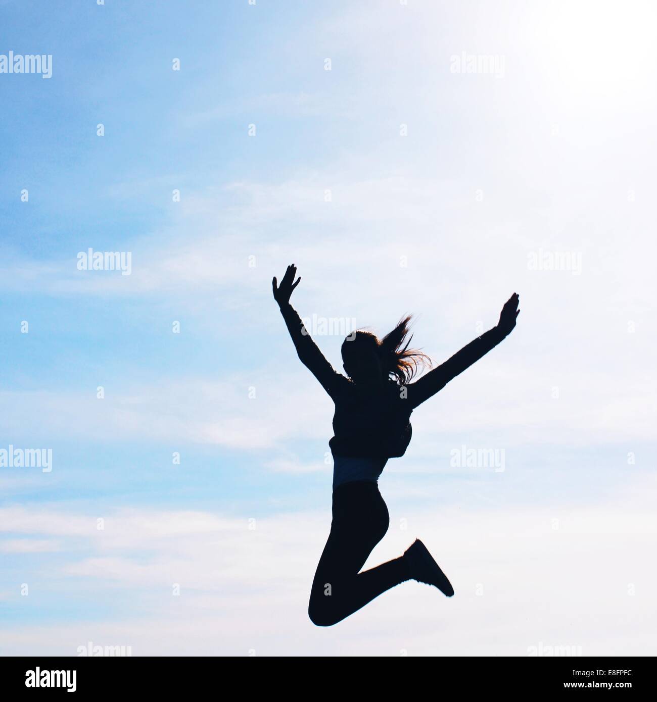 Silhouette d'un girl jumping mid air Banque D'Images