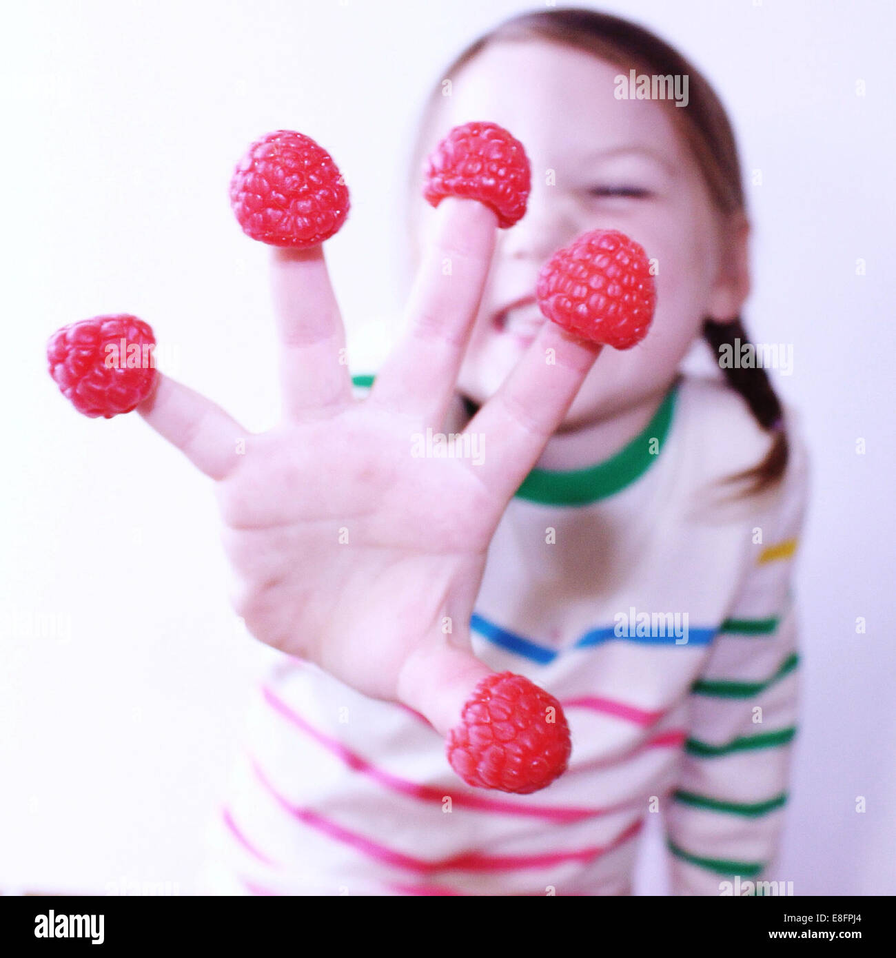 Fille avec framboises sur ses doigts Banque D'Images