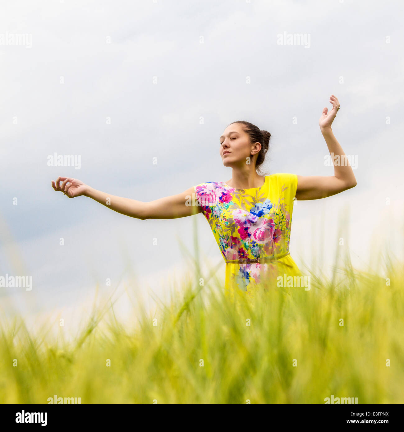 Femme en robe jaune dancing in field Banque D'Images