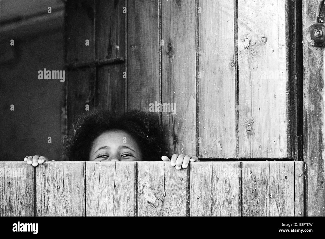 Girl peeking sur le bord d'une porte de l'écurie Banque D'Images