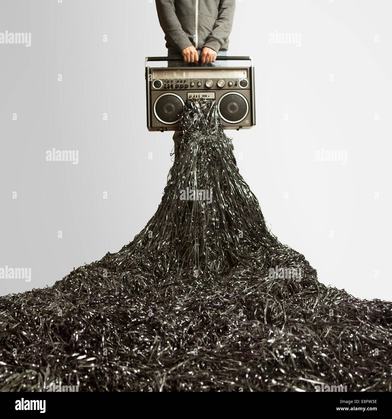 Homme tenant un enregistreur de cassette vintage avec de la bande débordant hors de lui Banque D'Images