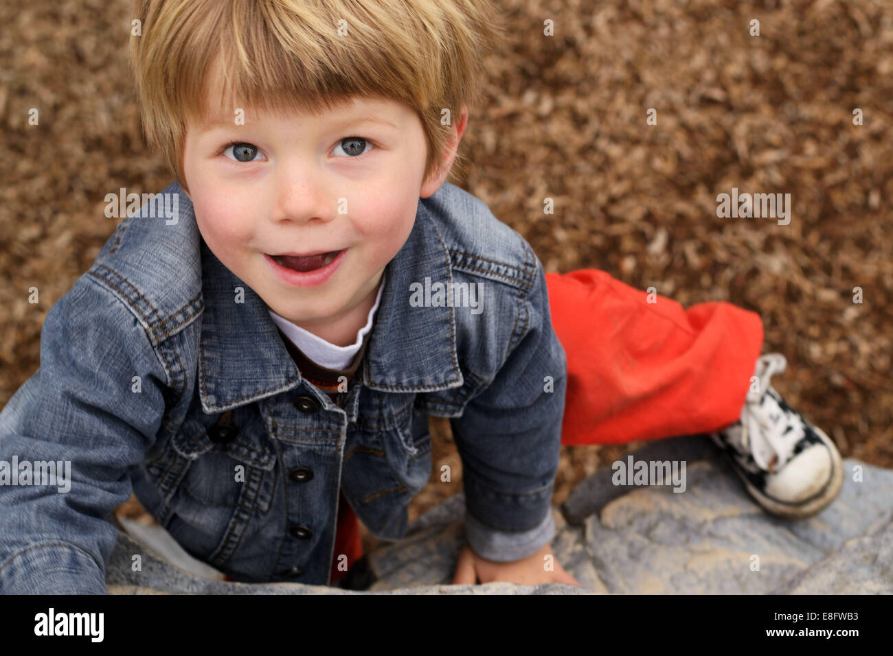 Portrait d'un garçon souriant grimpant sur un rocher Banque D'Images