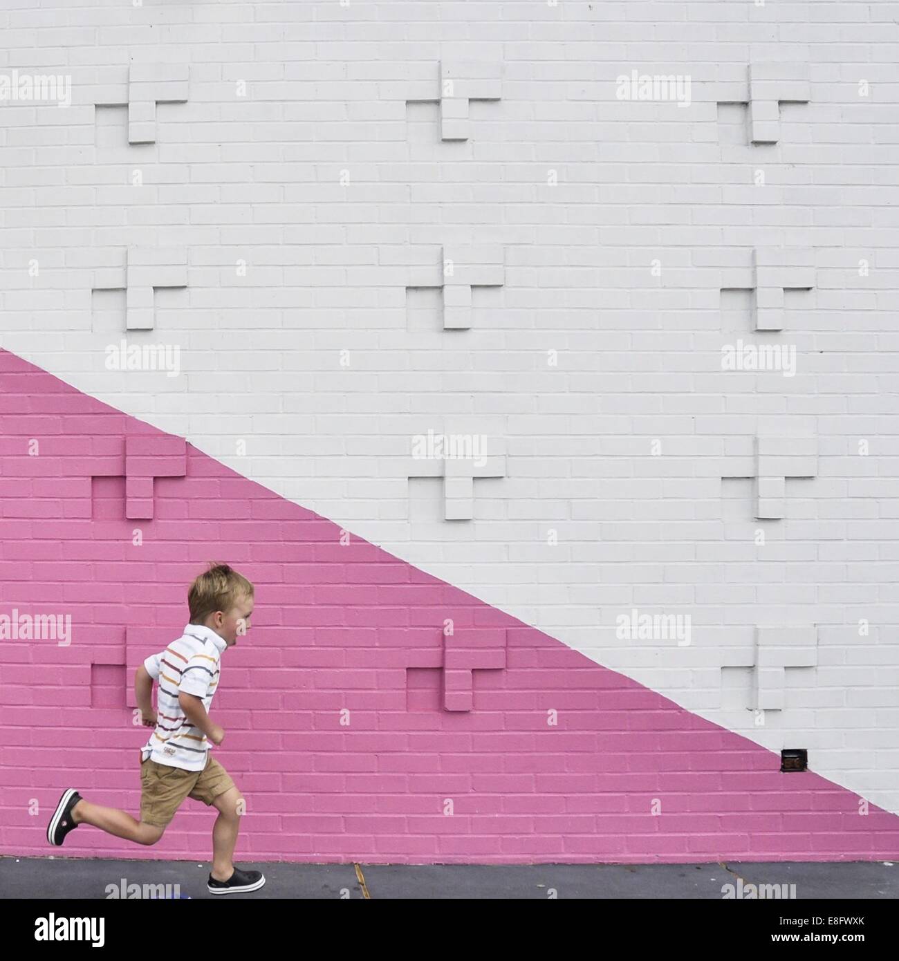 Boy running passé mur rose et blanc Banque D'Images