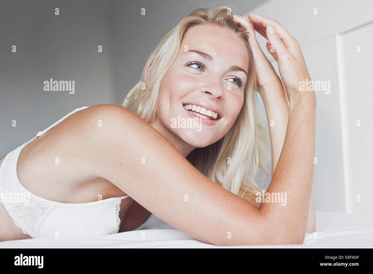 Portrait d'une femme blonde souriante couché sur un lit Banque D'Images