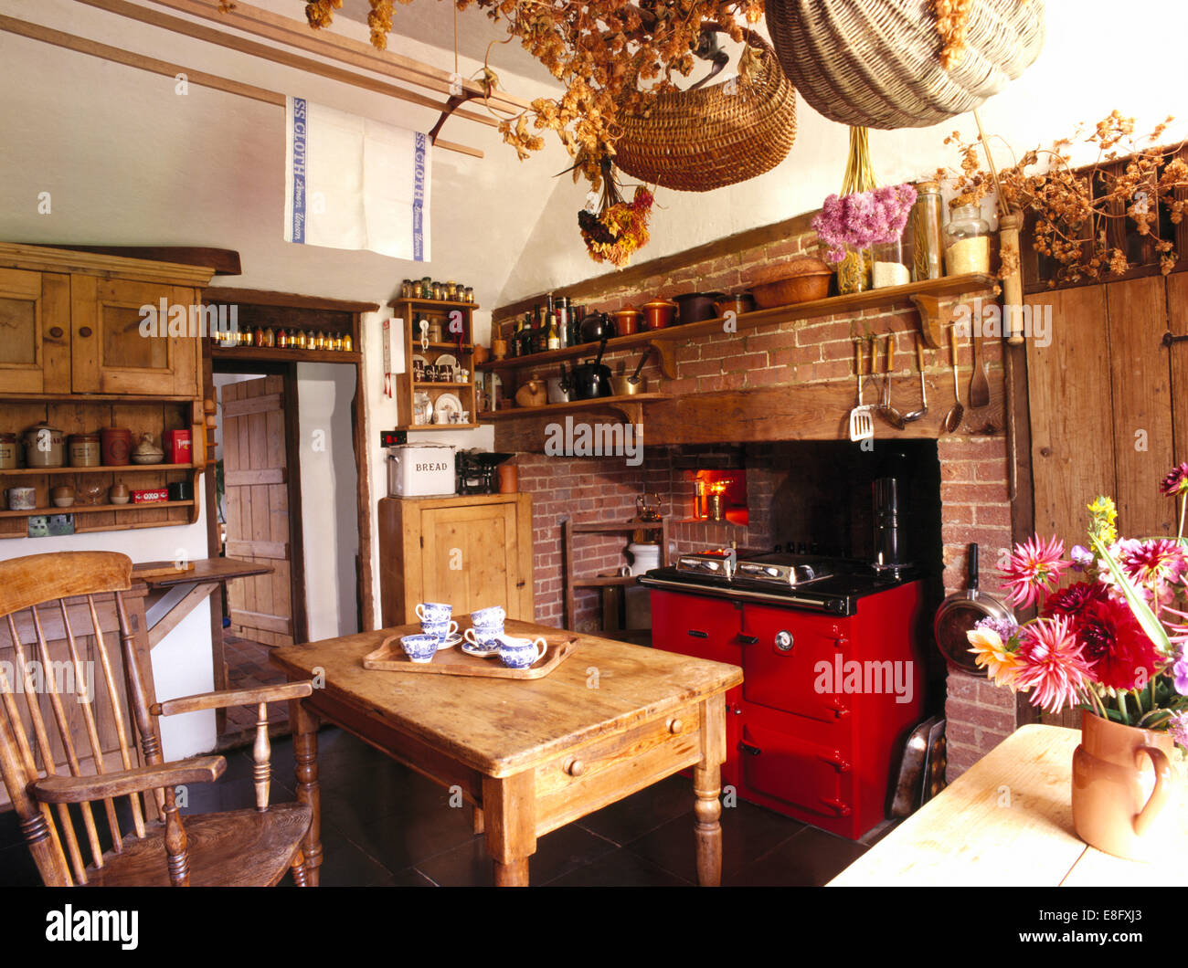 Paniers sur rack en bois au-dessus de table en vieux pin country kitchen avec Aga rouge Banque D'Images