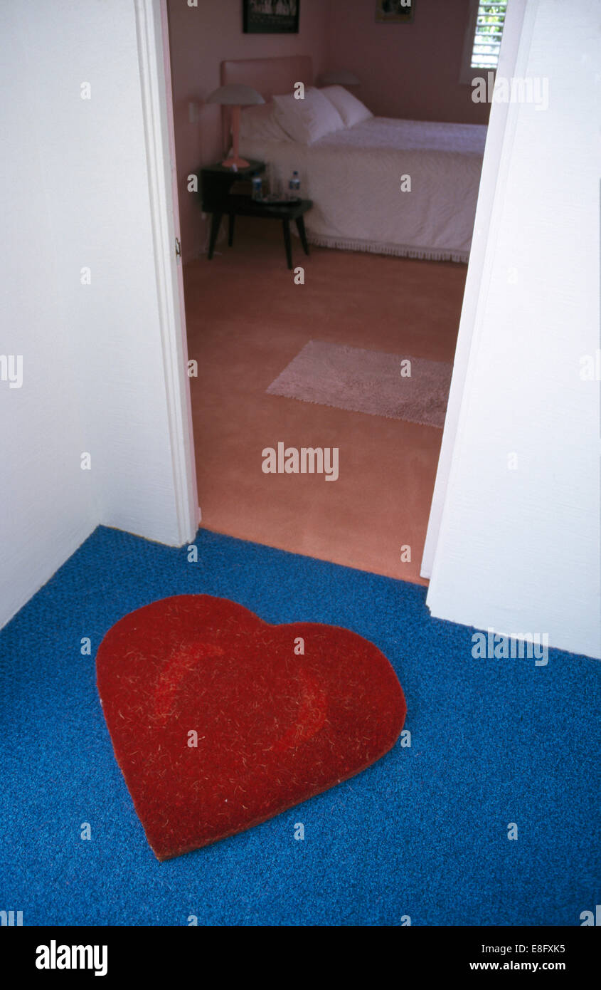 Tapis en forme de cœur rouge sur bleu marbre sur palier avec porte ouverte à la chambre à coucher moderne Banque D'Images