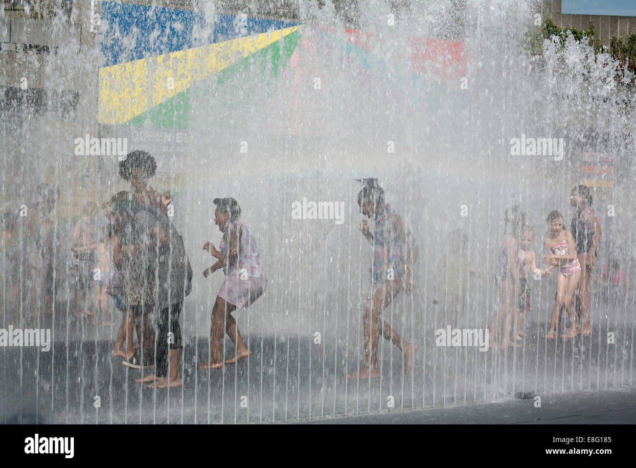 Enfants jouant et se mettre à l'eau vu à travers la fontaine sur South Bank London Banque D'Images
