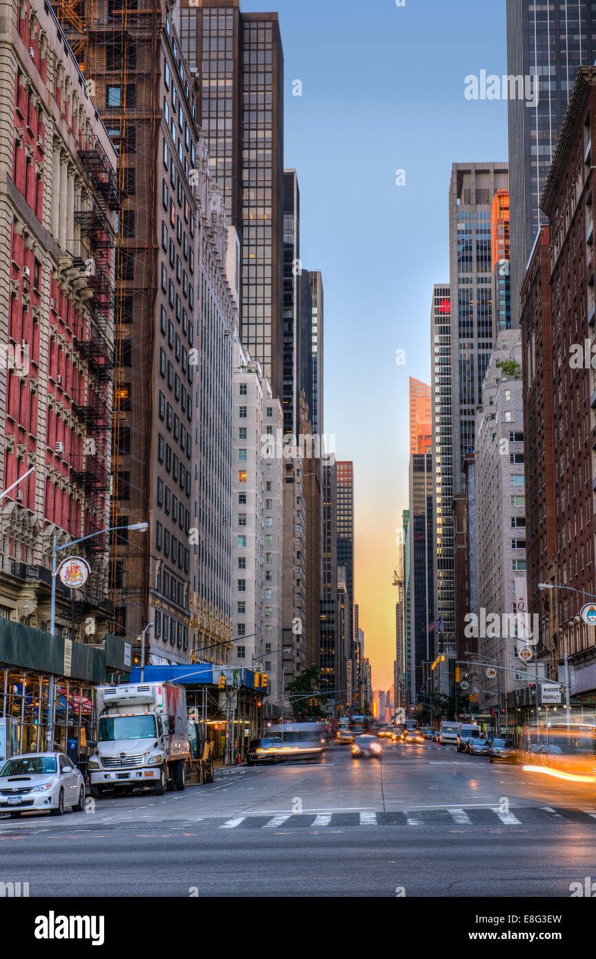 Tôt le matin, le trafic sur l'Avenue des Amériques comme le soleil se lève sur la partie basse de Manhattan au loin. Banque D'Images
