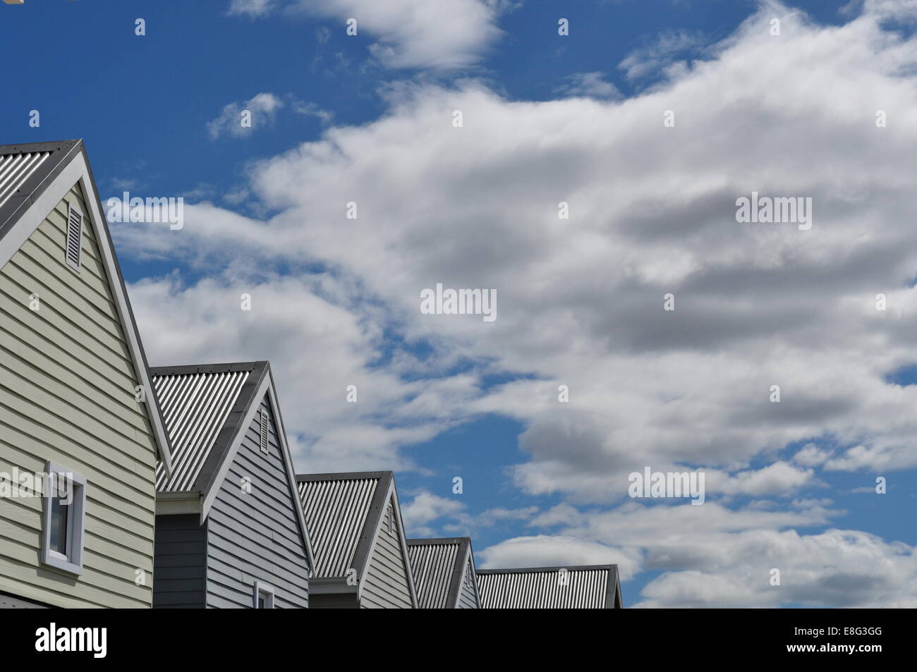 Cap au Nord dans le paysage nordique : une rangée de maisons construites dans l'architecture en bois typique, ciel bleu et nuages Banque D'Images