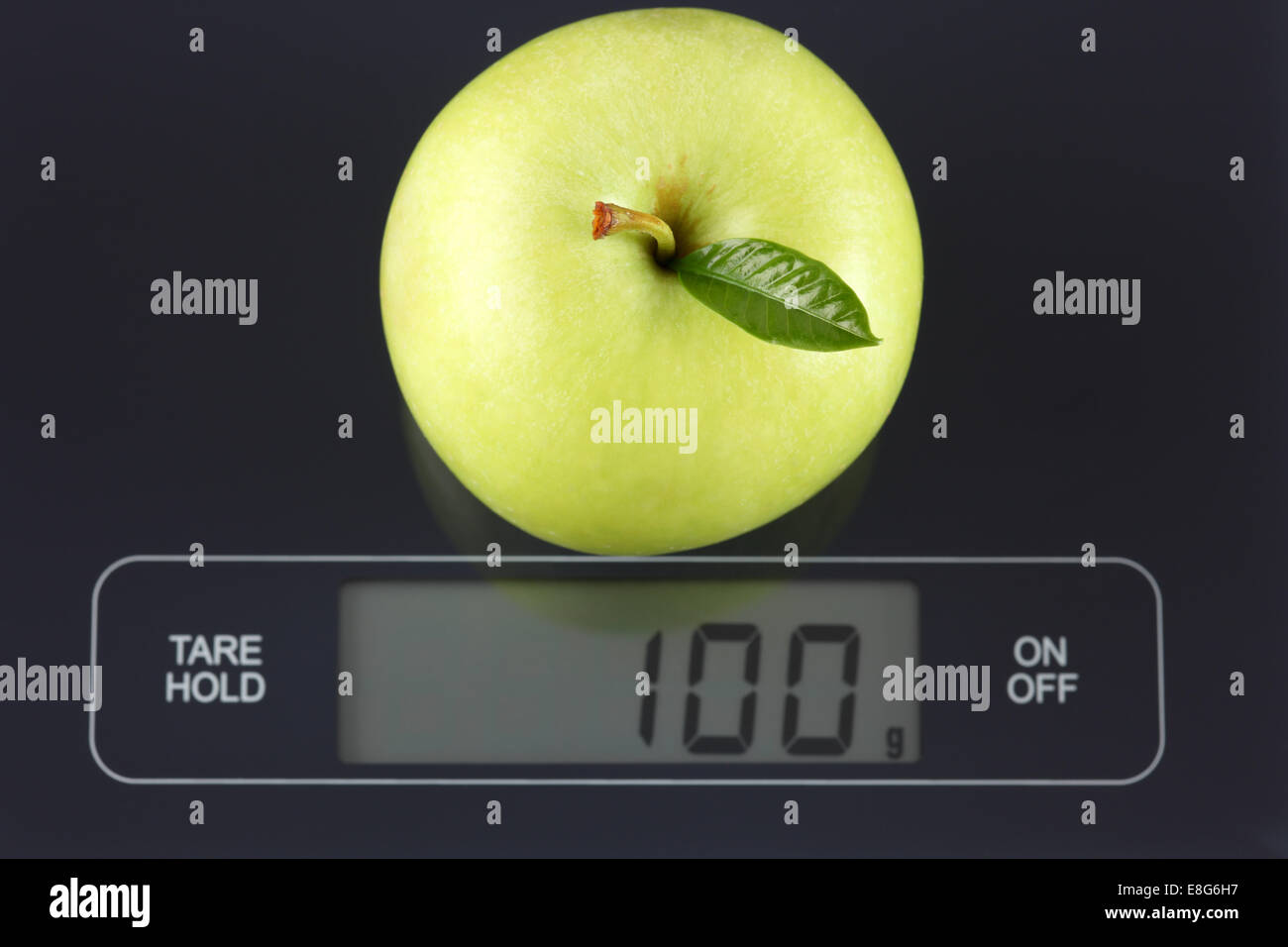 Green Apple sur l'échelle numérique affichant 100 grammes. Banque D'Images