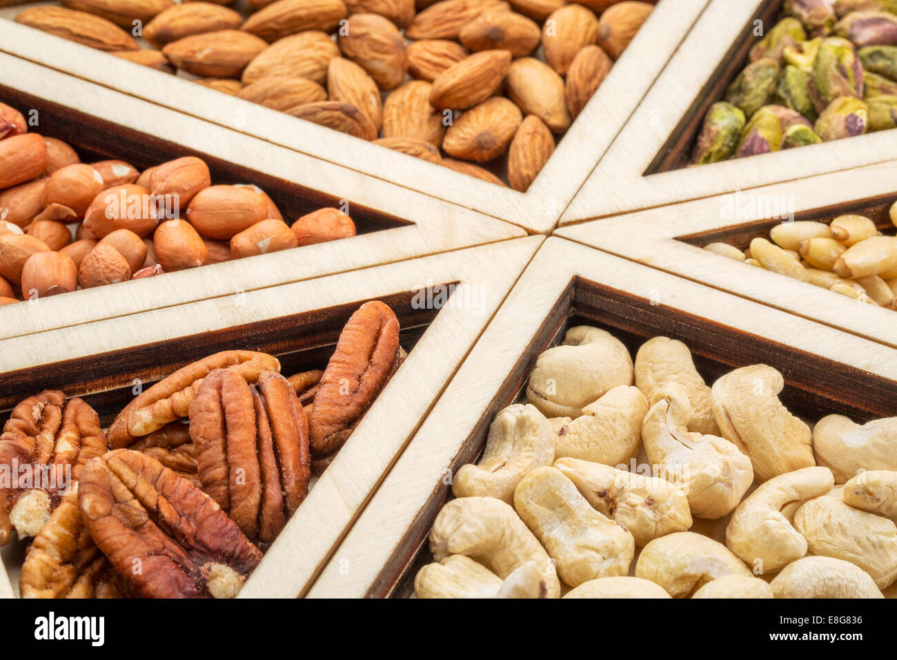 Variété de noix (de pécan, noix de cajou, amandes, pistaches, pin, arachide) dans un bac en bois géométriques Banque D'Images