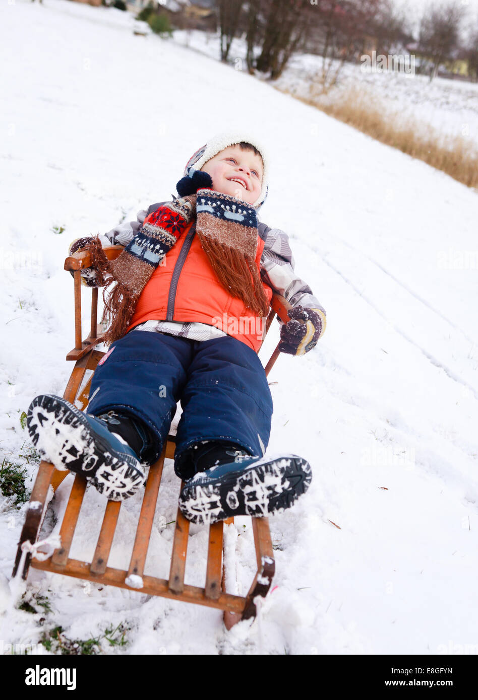 Garçon enfant sur un traîneau dans la neige Banque D'Images