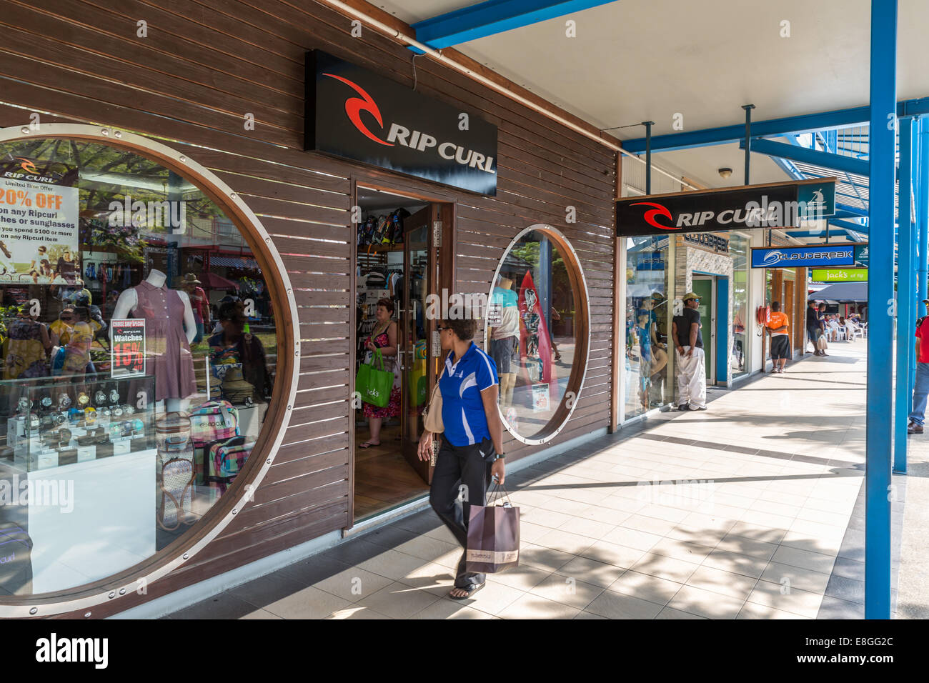 Jeune femme en passant devant la boutique Rip Curl dans cité touristique à Port Denarau, Fidji Banque D'Images
