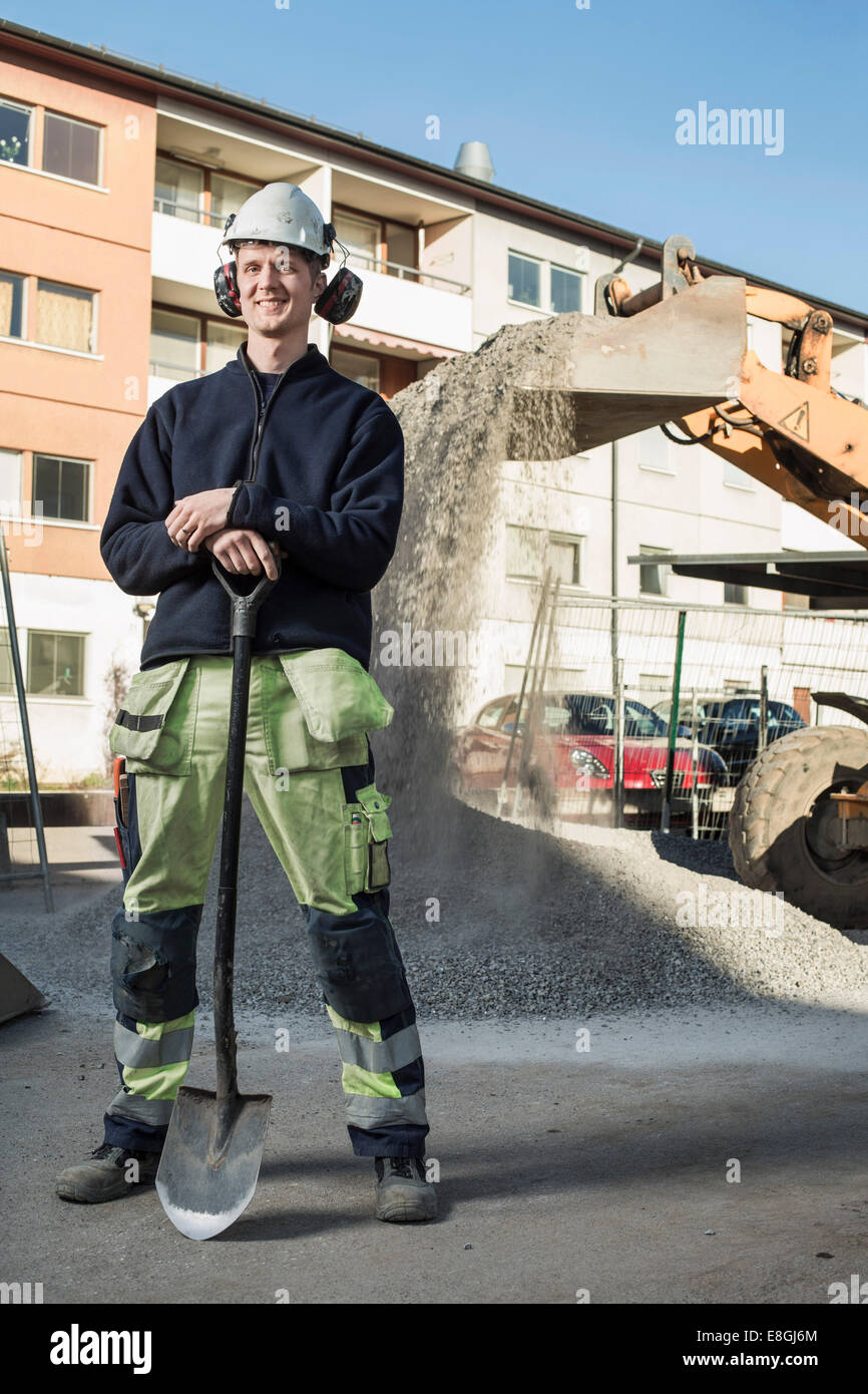 Full Length portrait of smiling worker avec pelle debout sur le site Banque D'Images