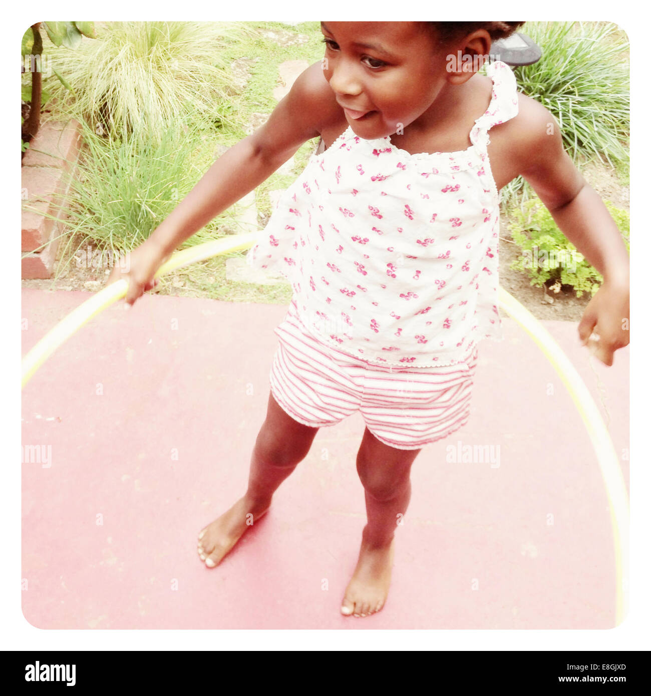 Fille debout dans un jardin jouant avec un hoop hula, San Francisco, Californie, États-Unis Banque D'Images