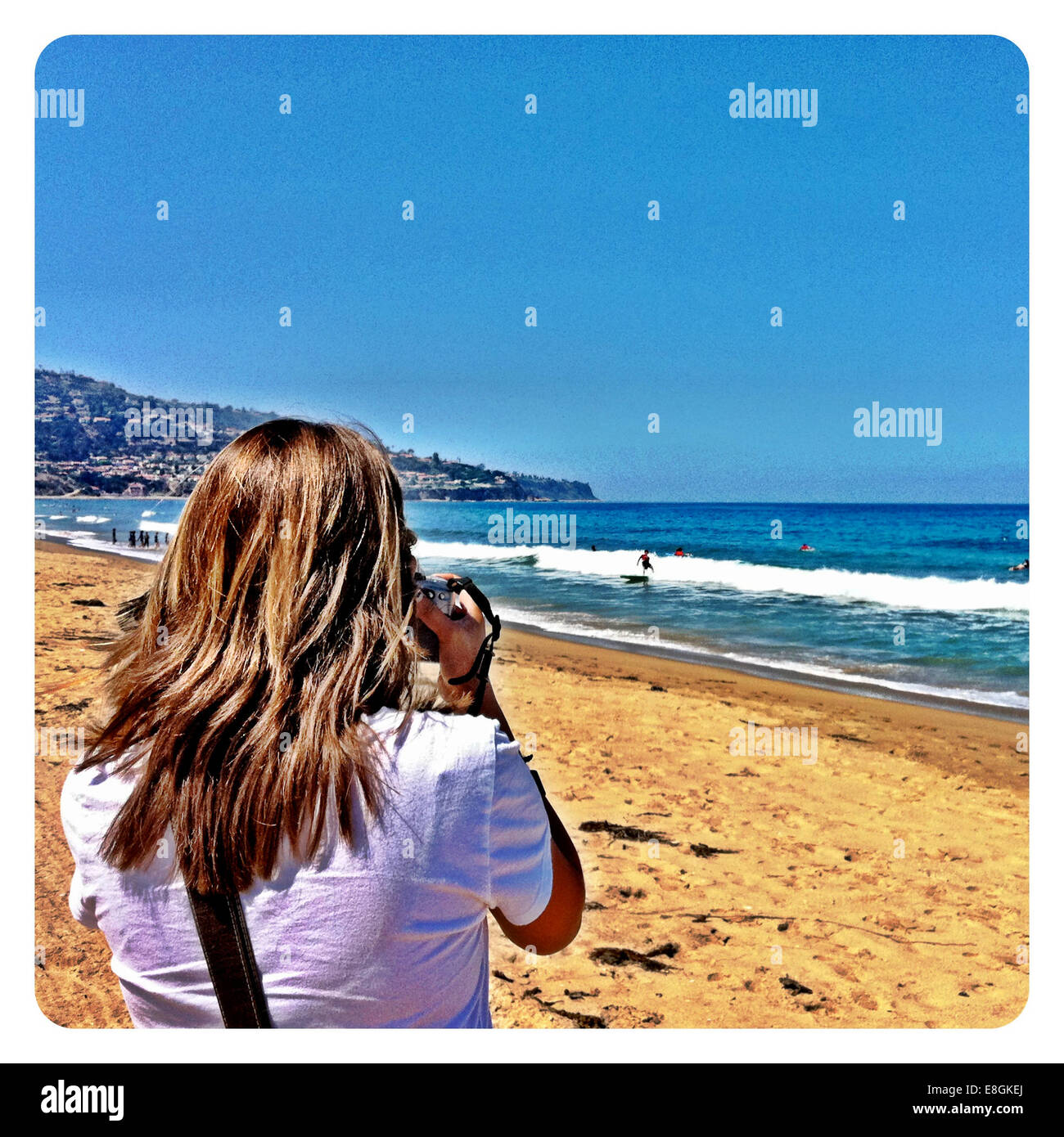 Vue arrière d'une femme prenant une photo sur la plage Banque D'Images