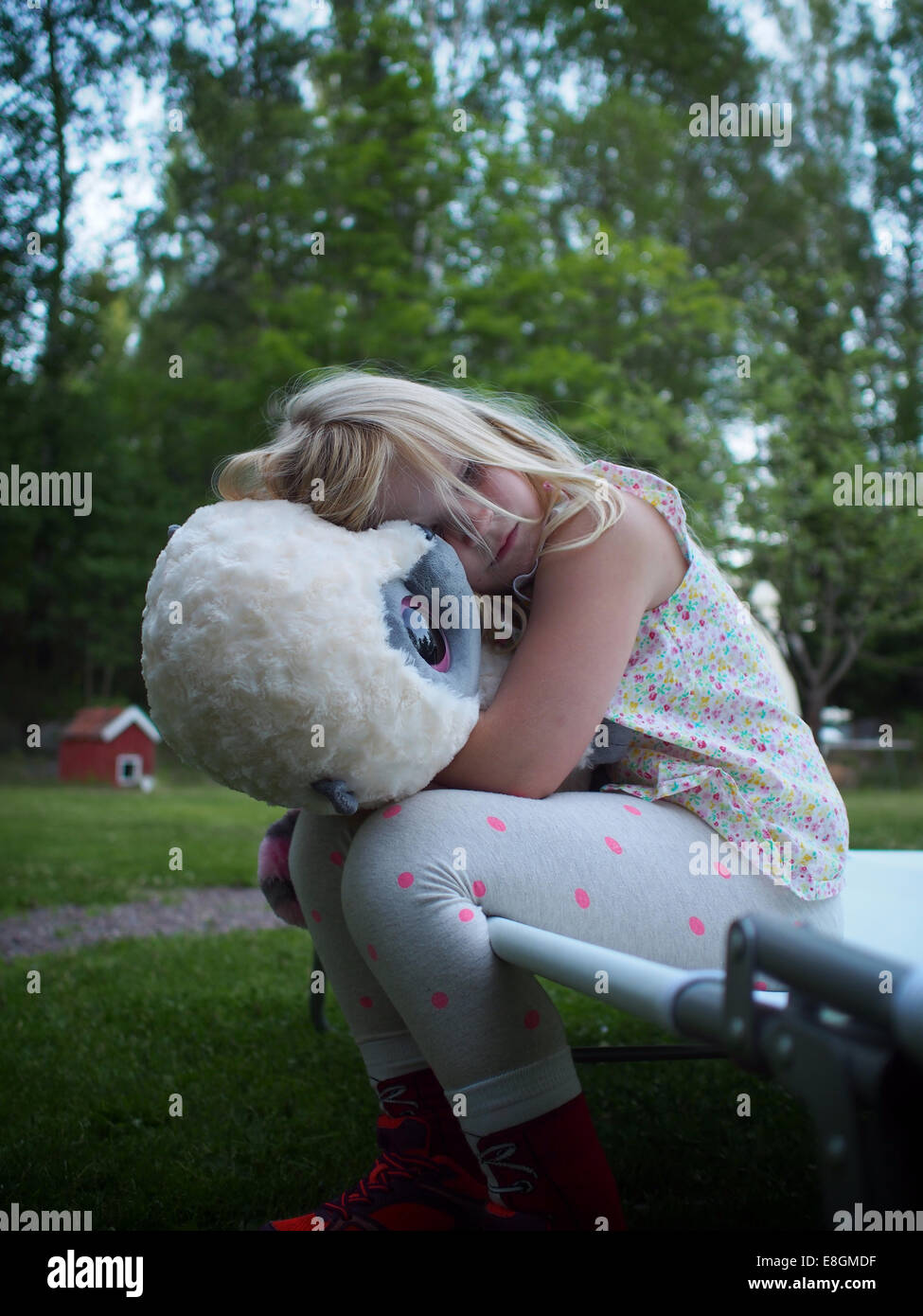 La Suède, Girl (6-7) hugging teddy bear in backyard Banque D'Images