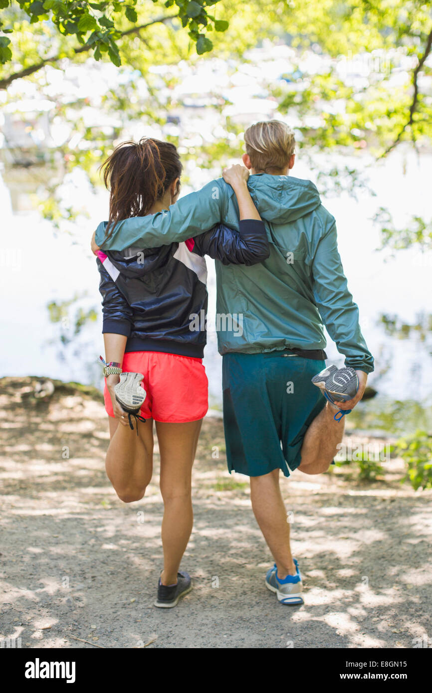 Vue arrière sur toute la longueur du couple doing stretching exercices ensemble au Lakeshore Banque D'Images