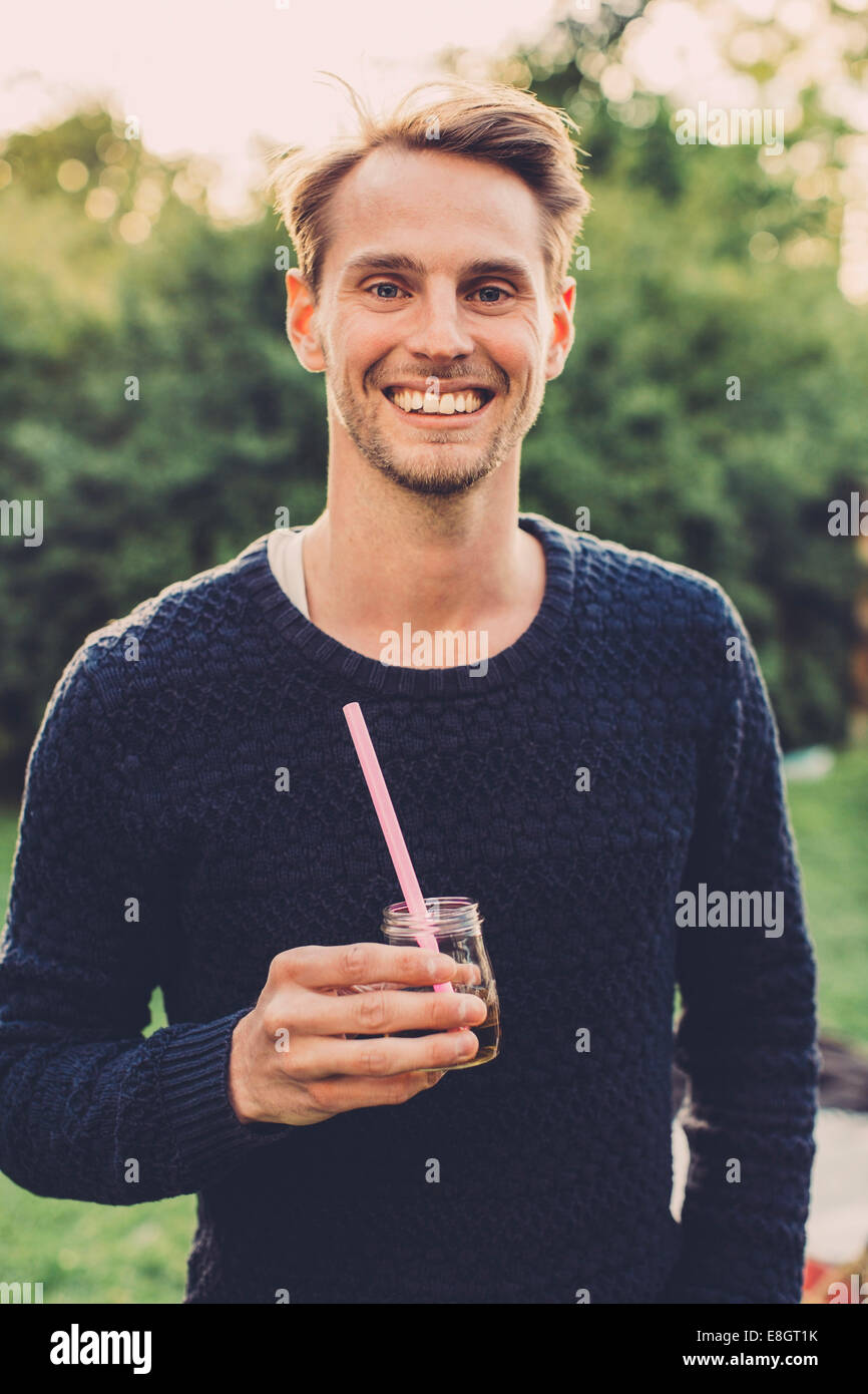 Portrait of happy man holding sureau verre sur roof garden Banque D'Images