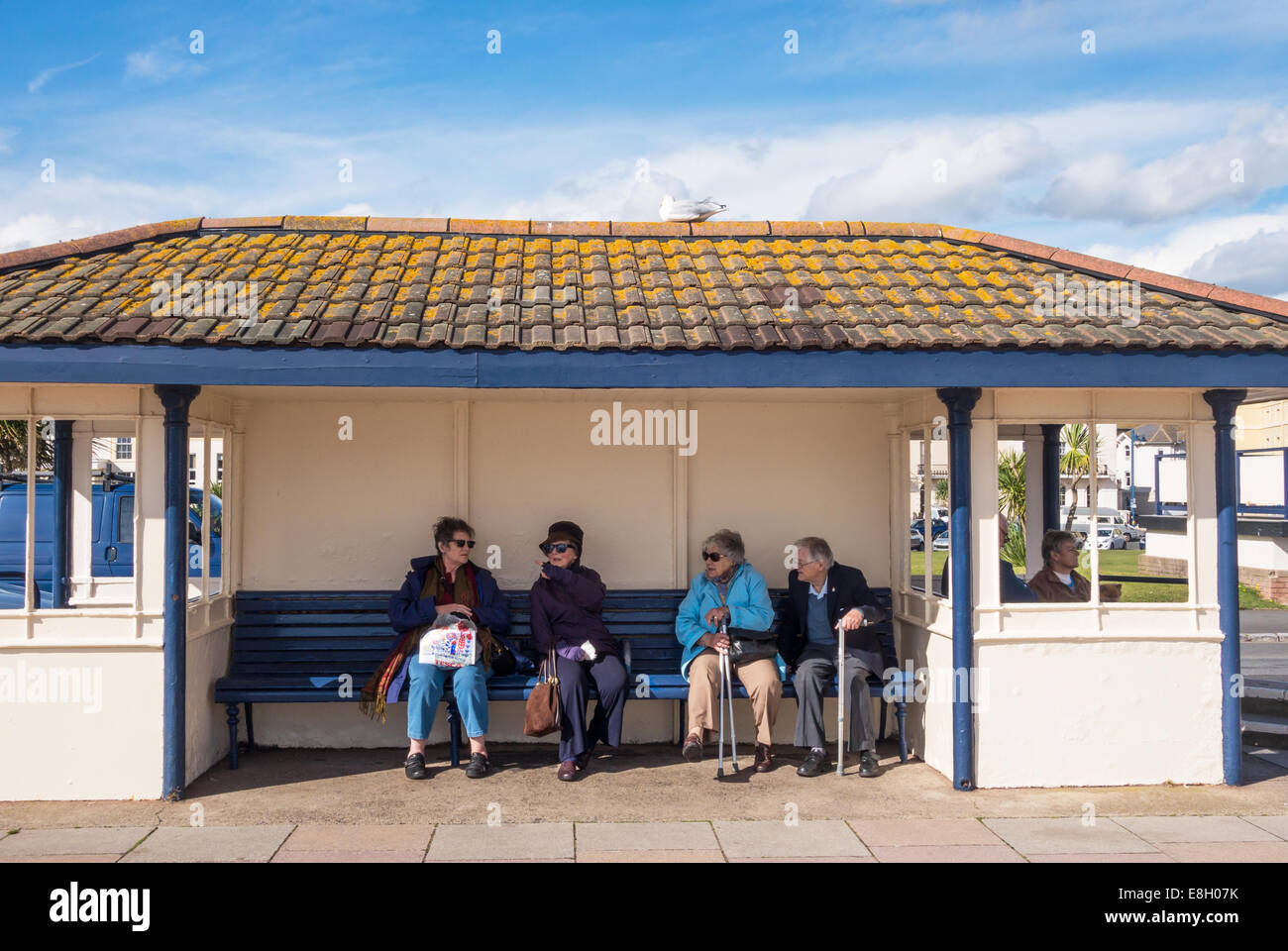 Quatre retraités, 3 femelles et 1 mâle assis sur la promenade à Teignmouth dans le Devon. Banque D'Images