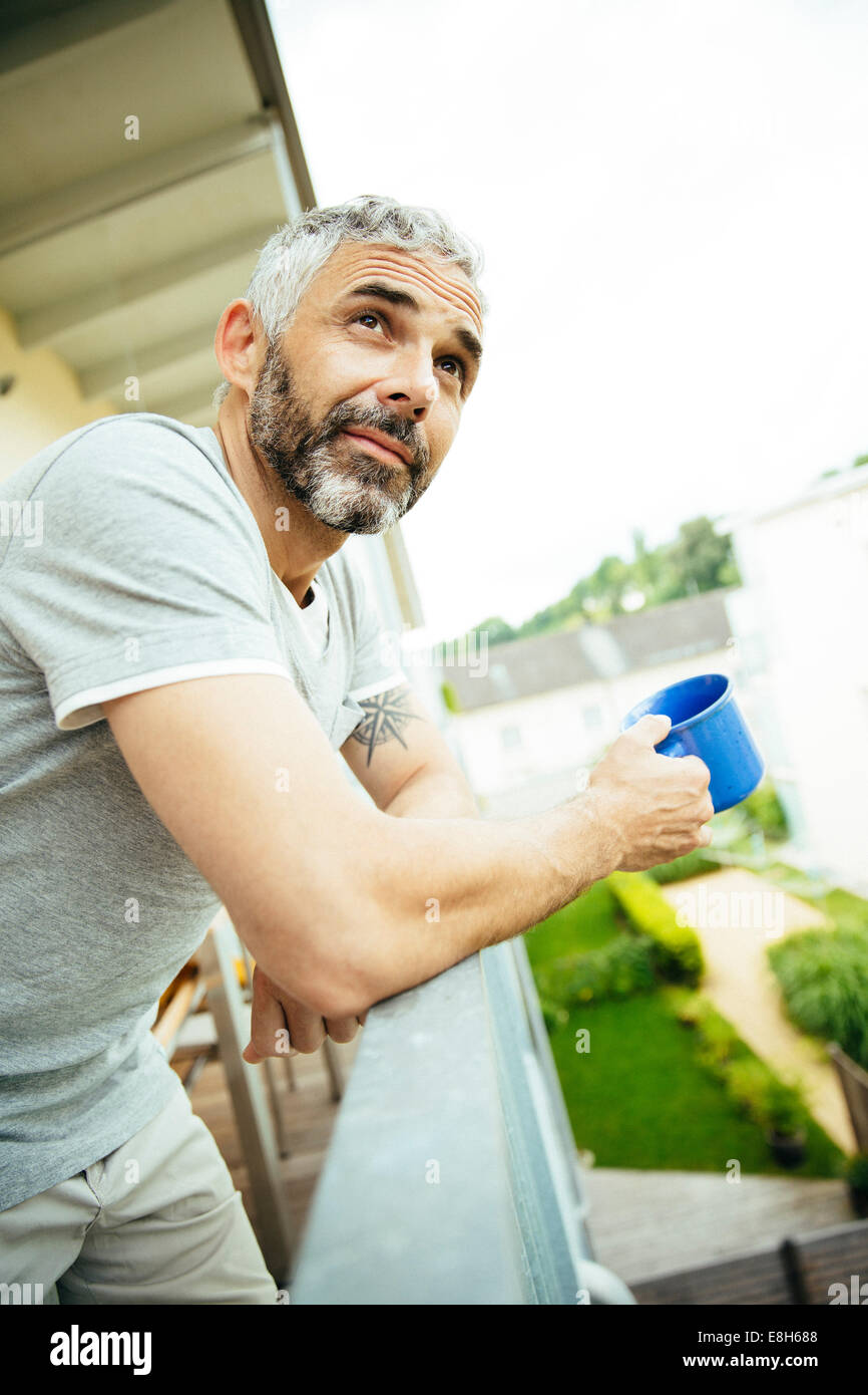 Portrait de l'homme reposant, avec tasse de café sur son balcon Banque D'Images