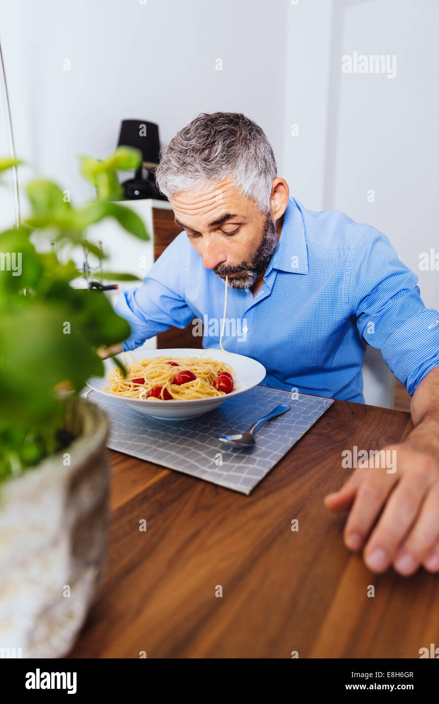 Man eating pasta dans sa cuisine Banque D'Images