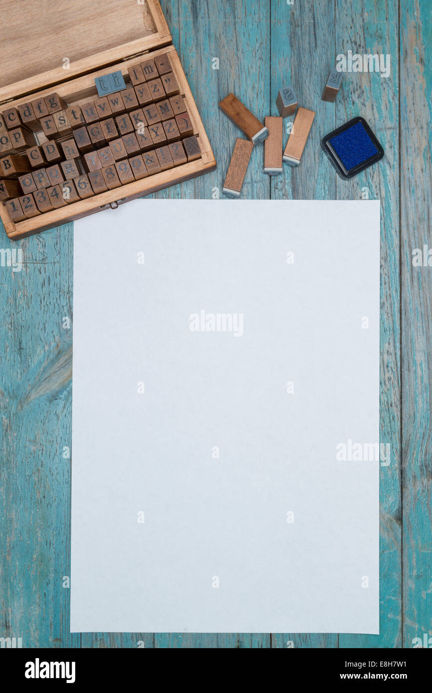 Feuille de papier blanc, boîte en bois, des timbres et une lettre en bois tampon encreur Banque D'Images