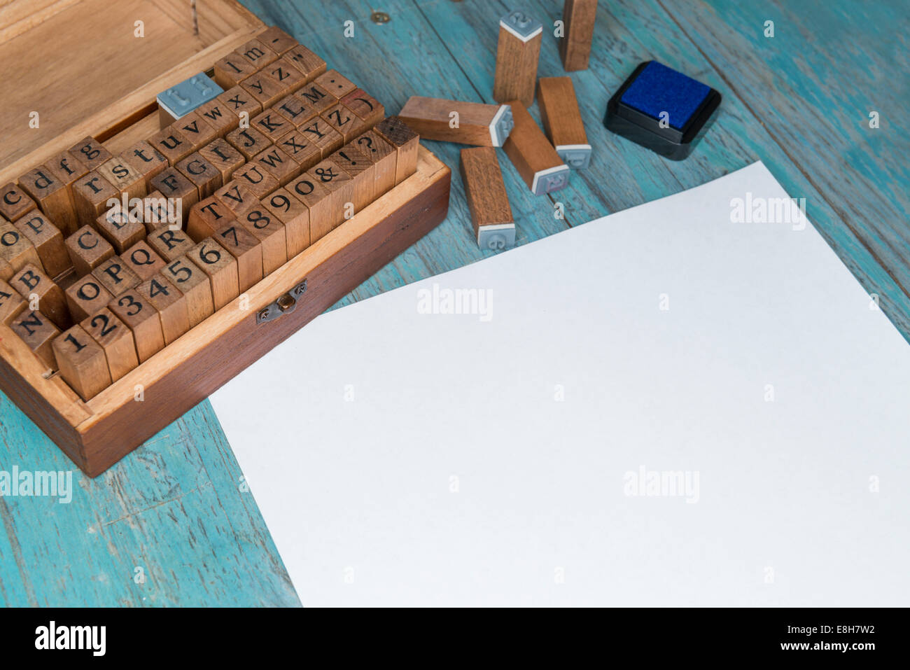 Feuille de papier blanc, boîte en bois, des timbres et une lettre en bois tampon encreur Banque D'Images