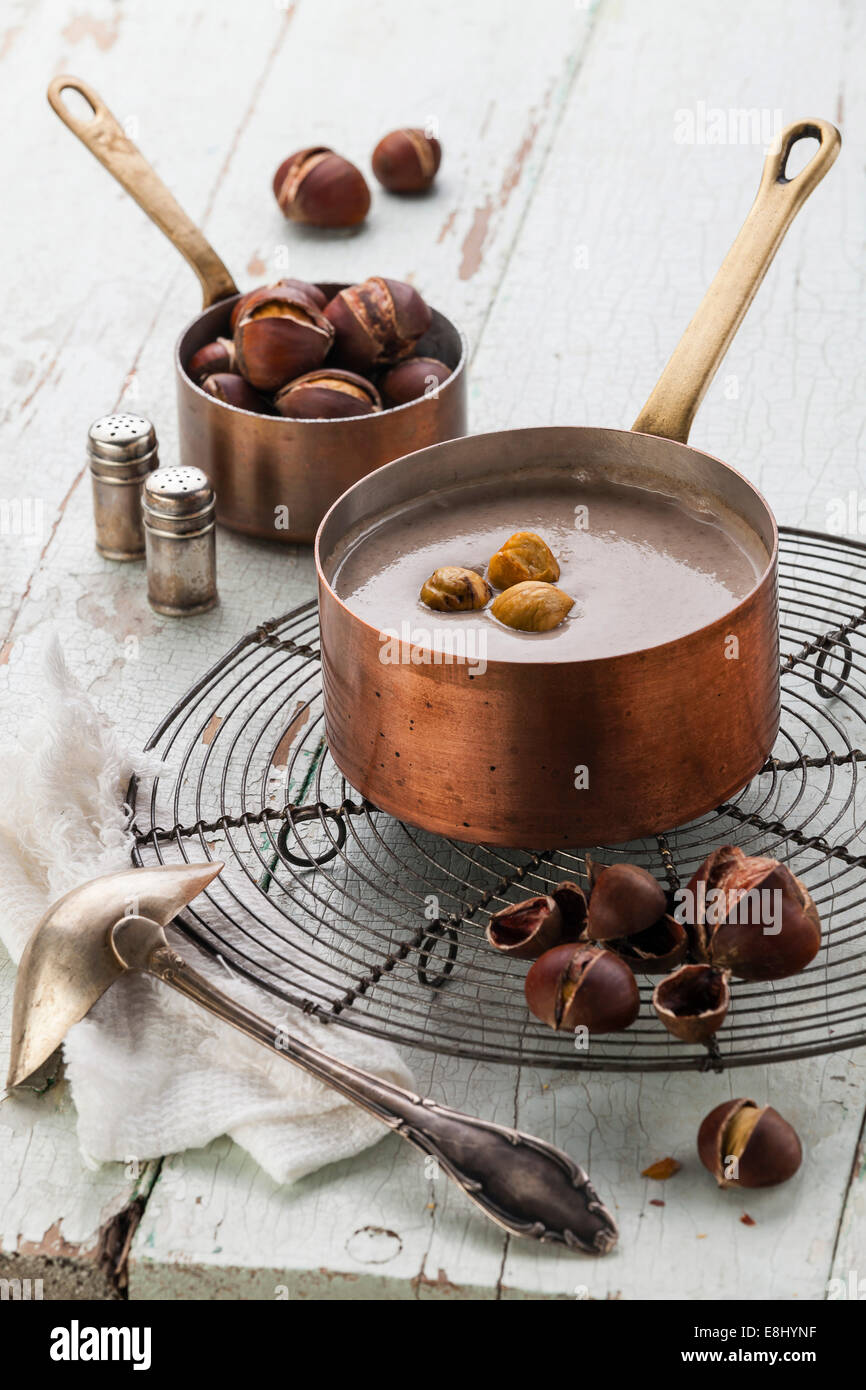 Soupe de châtaignes en marmite en cuivre avec des châtaignes grillées sur fond de texture bleu Banque D'Images