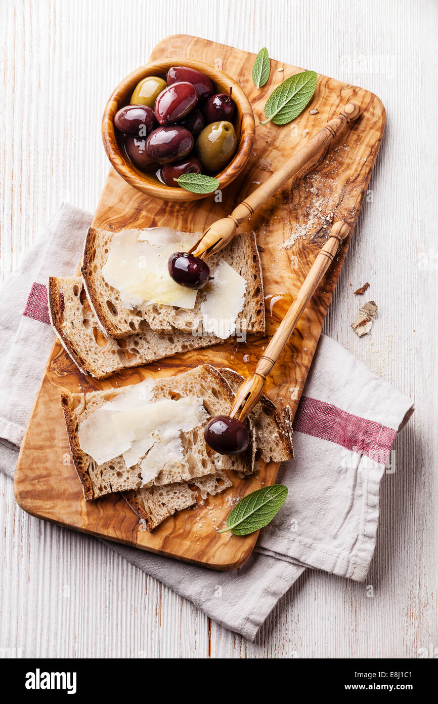 Des sandwichs de fromage Parmesan et olives sur une planche à découper en bois d'olivier Banque D'Images