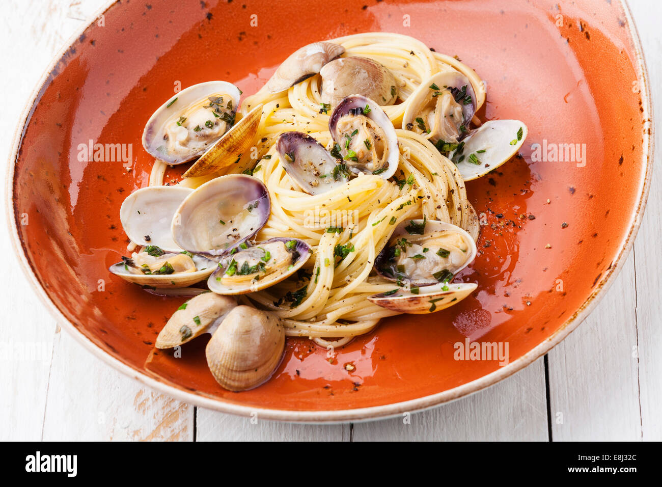 Pâtes aux fruits de mer Spaghetti alle vongole avec palourdes sur plaque orange Banque D'Images Pâtes aux fruits de mer Spaghetti alle vongole avec palourdes sur plaque orange Banque D'Images